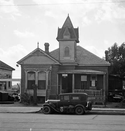 Black-and-white photograph of a historic house with a porch and steep roof