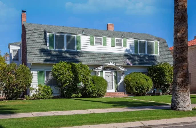 Encanto–Palmcroft home with a gambrel roof, green shutters, and a palm tree