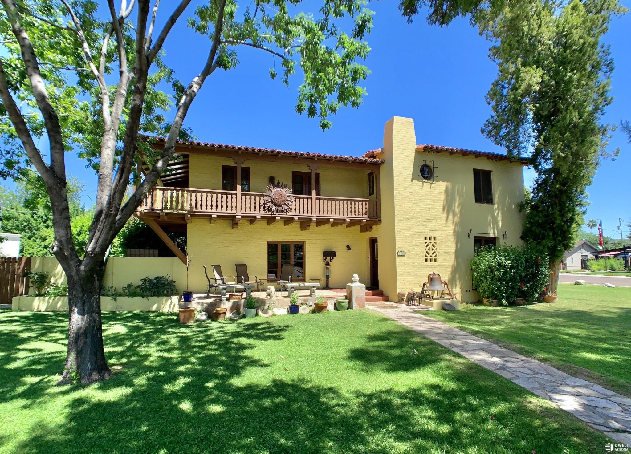 Two-story stucco Windsor Square residence with red tile roof accents, a balcony and mature shade trees