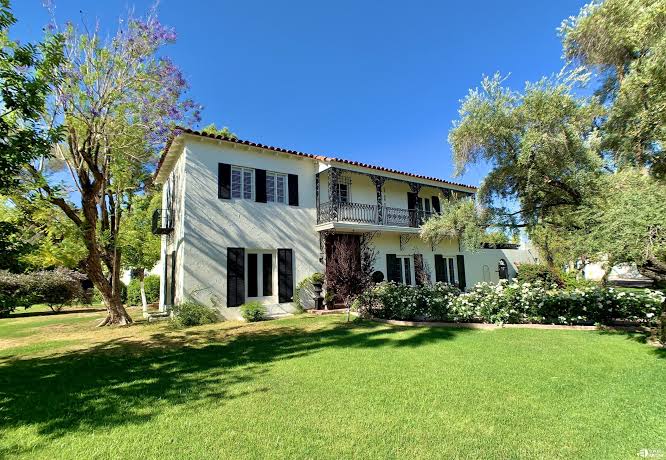 Two story Encanto Palmcroft home with shuttered windows and tree shaded lawn