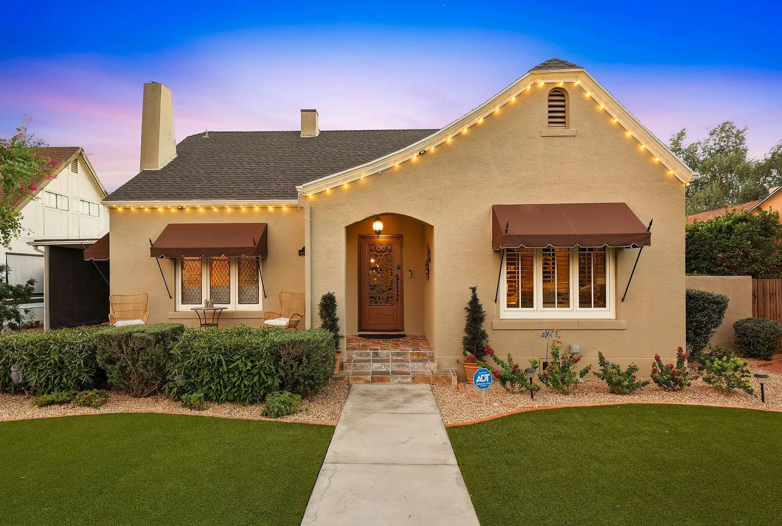 Stucco period home with arched porch at dusk
