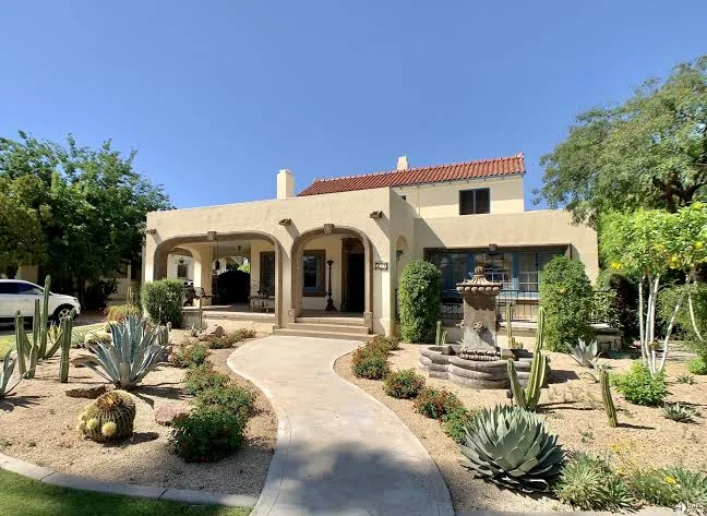 Stucco home with arched porch, red tile roof and desert landscaping