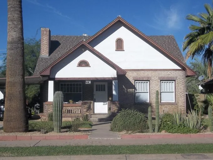 Brick period home with front gables, porch and desert landscaping