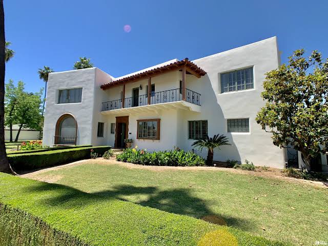 Two-story white stucco Windsor Square residence with flat rooflines, red tile accents and an upper balcony