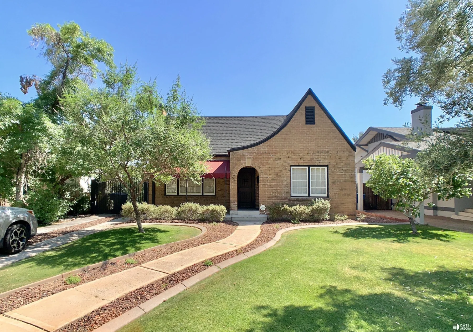 Brick period revival home with arched entry and front lawn