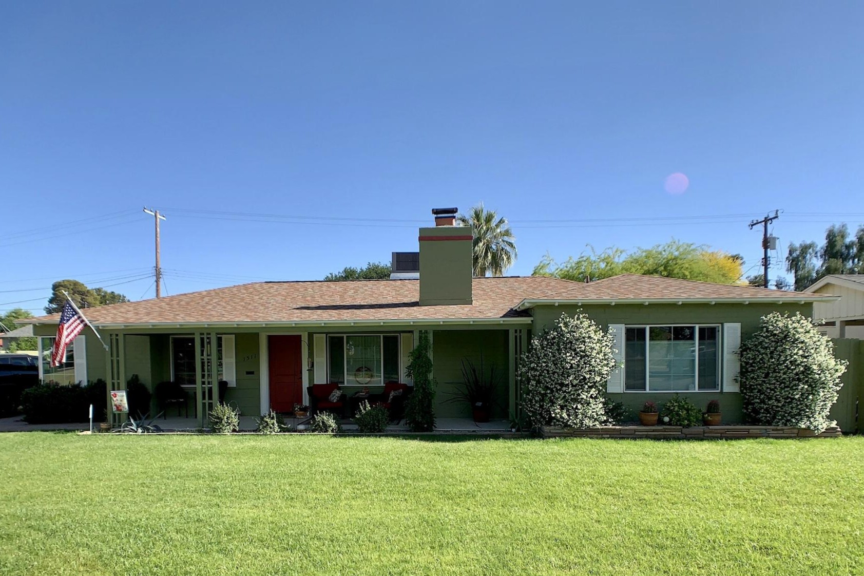 Long one-story green ranch house with a deep front porch