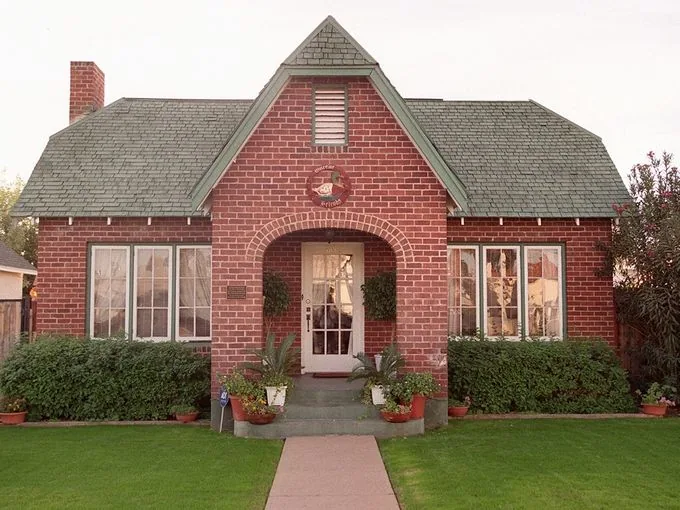 Red brick home with front gable and arched entry