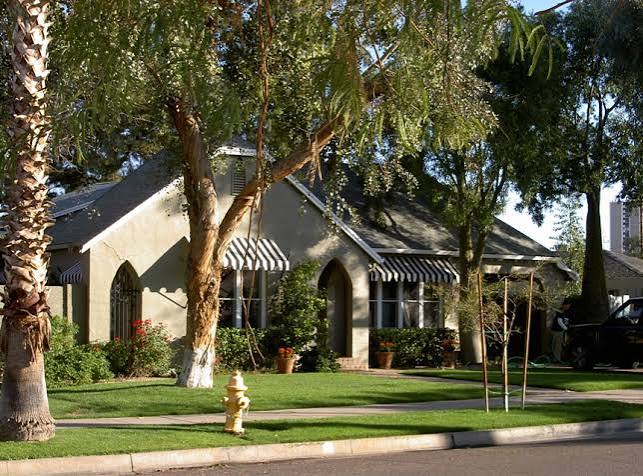 Shaded stucco Willo home with pointed arch entrance and window awnings