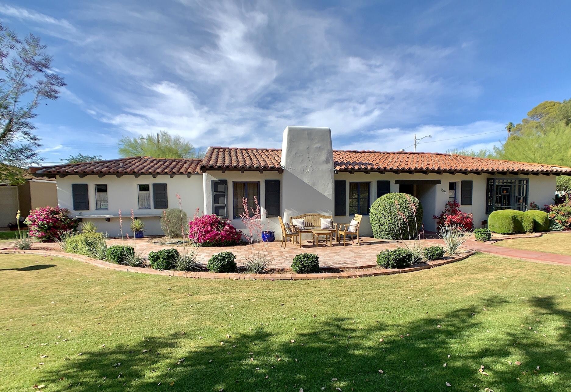 Long stucco house with red tile roof and central chimney