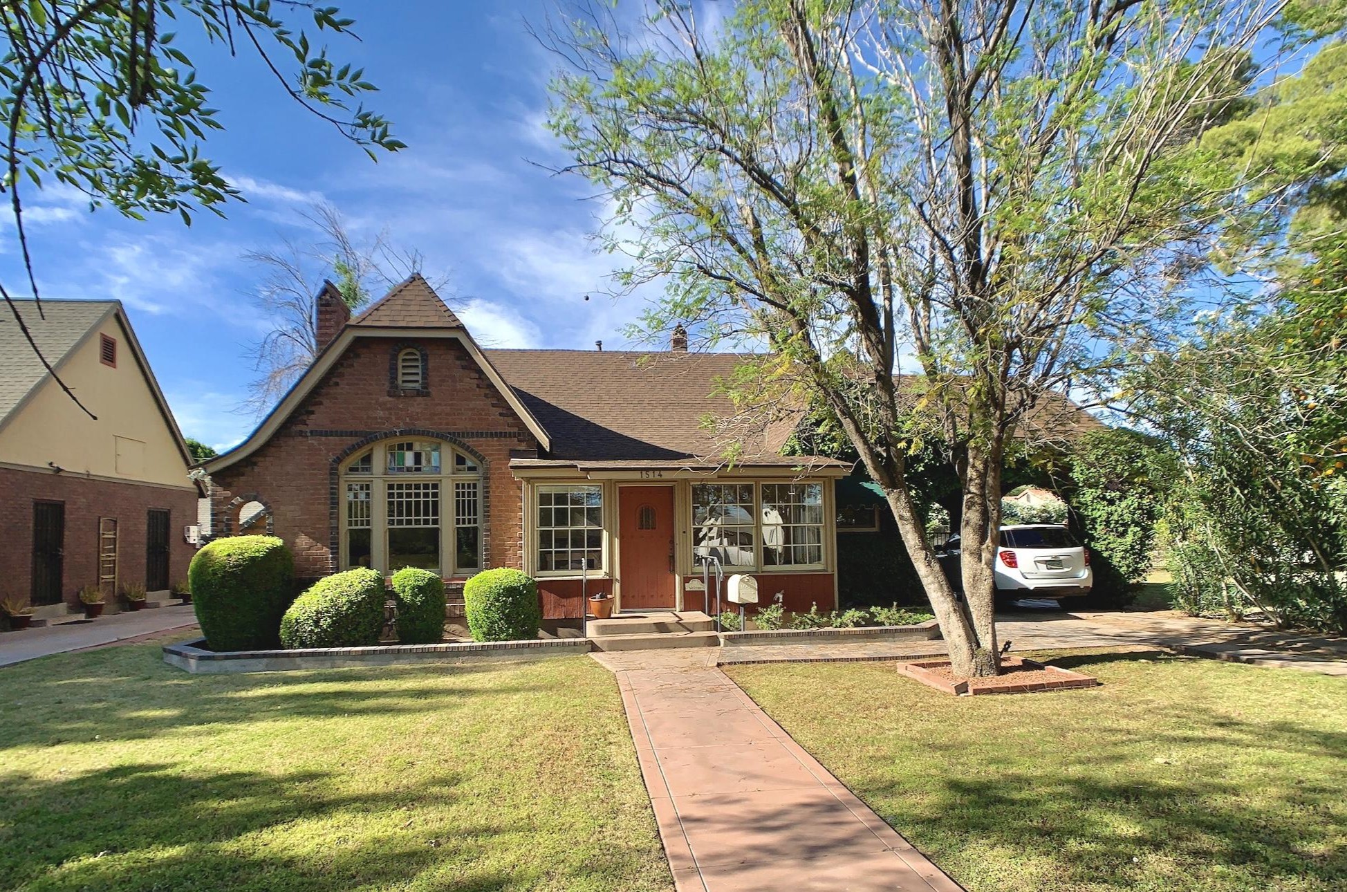 Brick cottage with a front gable, arched picture window and porch