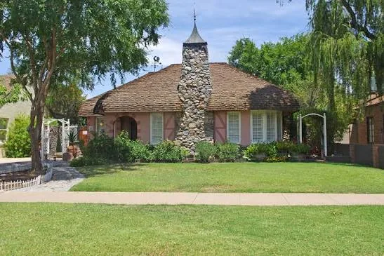 Historic home with a stone chimney and mature shade trees
